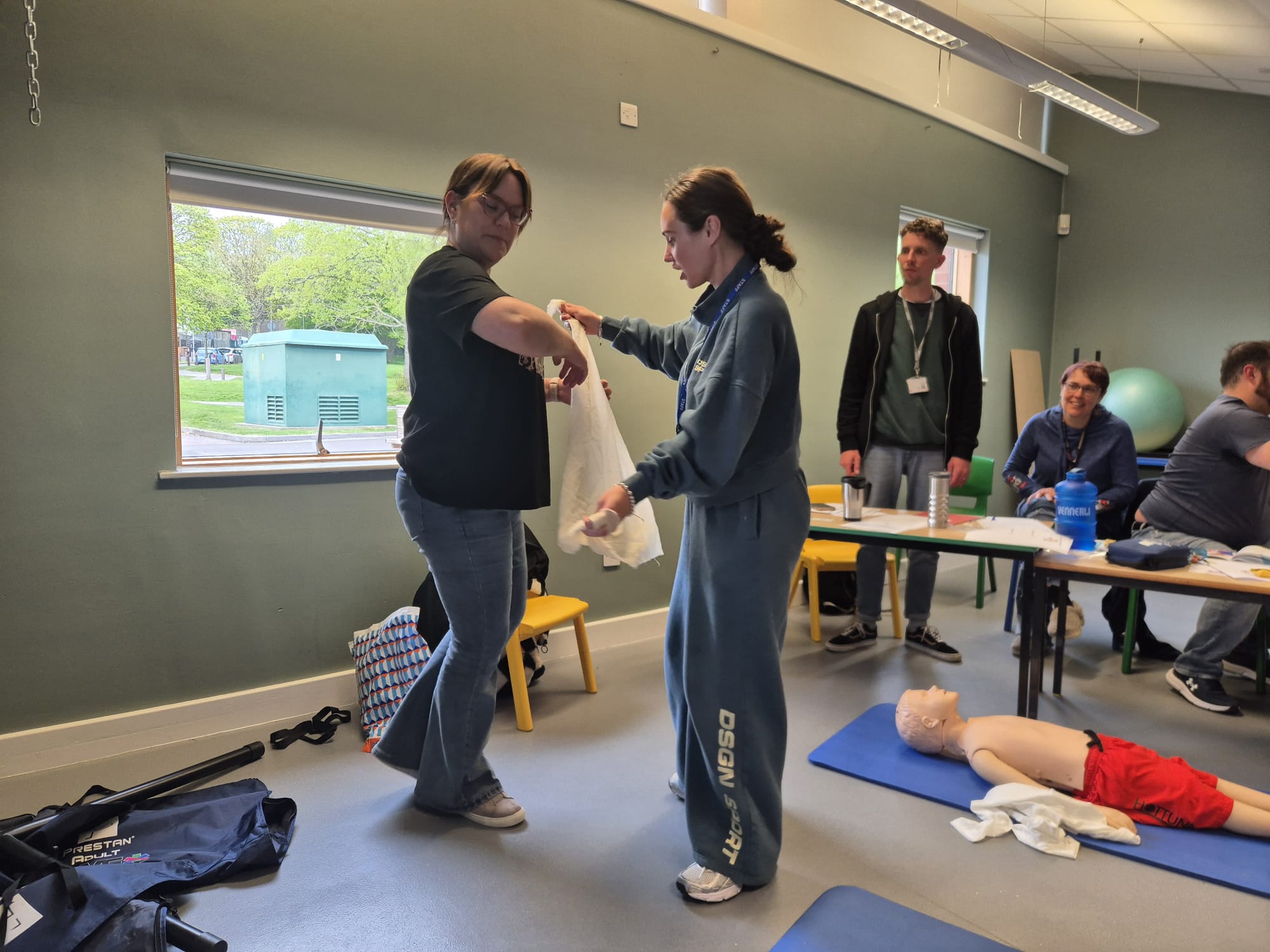 AWE Training first aid session with practical bandaging and CPR equipment